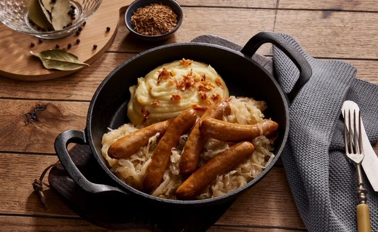 Fünf kleine Rostbratwürstchen vom Schwein auf herzhaftem Sauerkraut, dazu Kartoffelpüree mit Röstzwiebeln