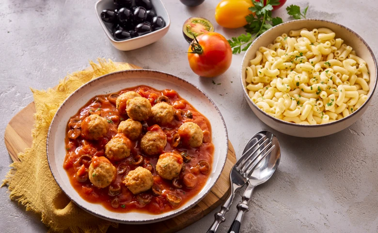 Geflügelbällchen in Tomatensugo mit Oliven, dazu Hörnchennudeln