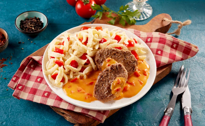 Zwei Rinderfrikadellen in Soße in Paprika-Rahmsoße mit ganzen Paprikastücken, dazu Spätzle