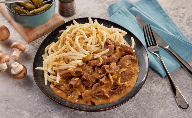 "Boeuf Stroganoff" mit Champignons, Zwiebeln und Gurkenstreifen in Rahmsoße, dazu Eierspätzle mit Brösel-Garnitur