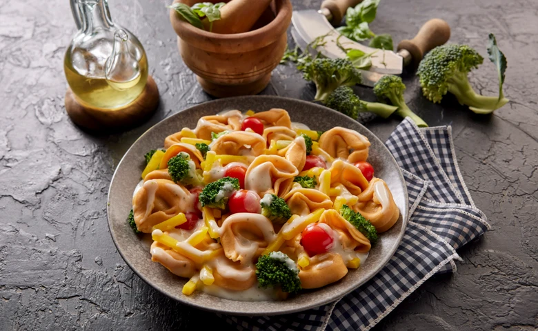 Tortelloni "Primavera" mit Kirschtomaten, Brokkoli und gelben Möhren in feiner Frischkäse-Käsesoße, abgerundet mit Bärlauch